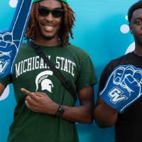 two students posing in front of CAB backdrop at Laker Kickoff photo booth with foam fingers